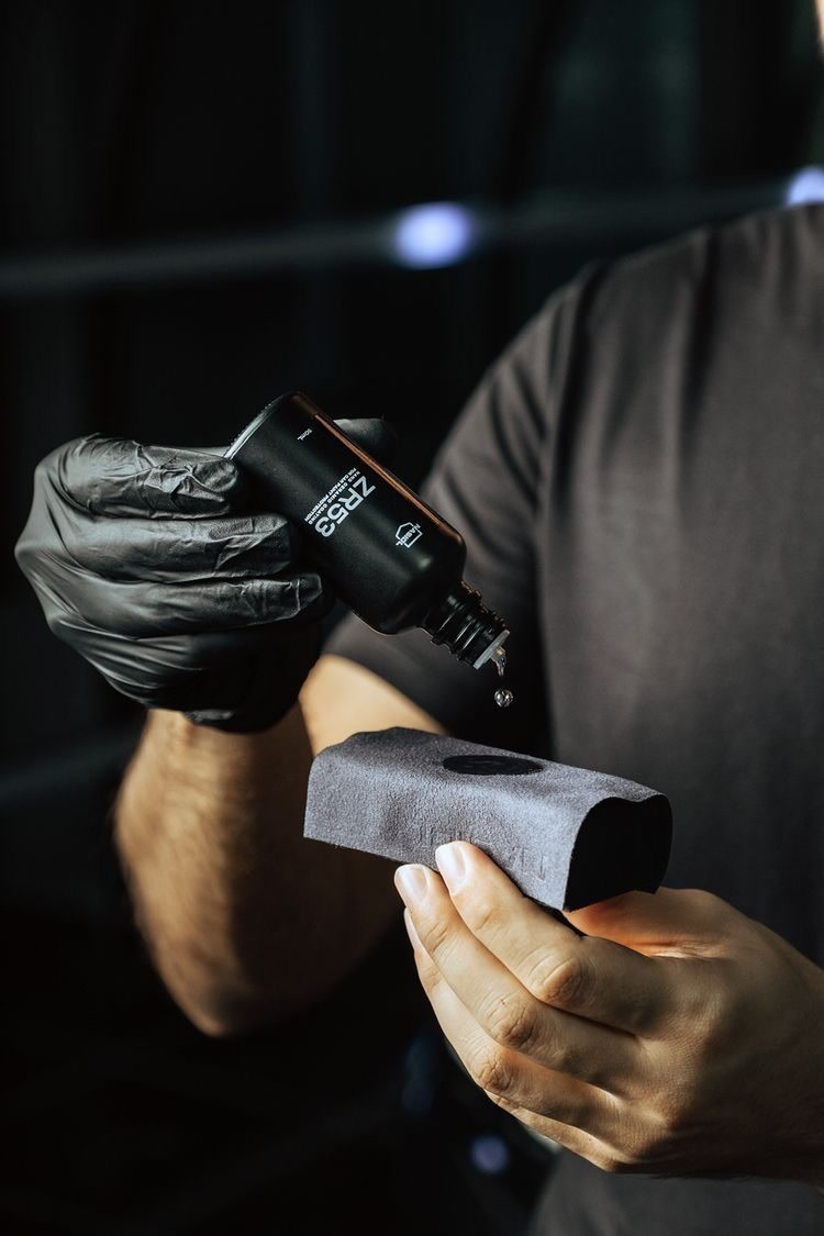 Aplicador con guantes negros sobre pintura oscura