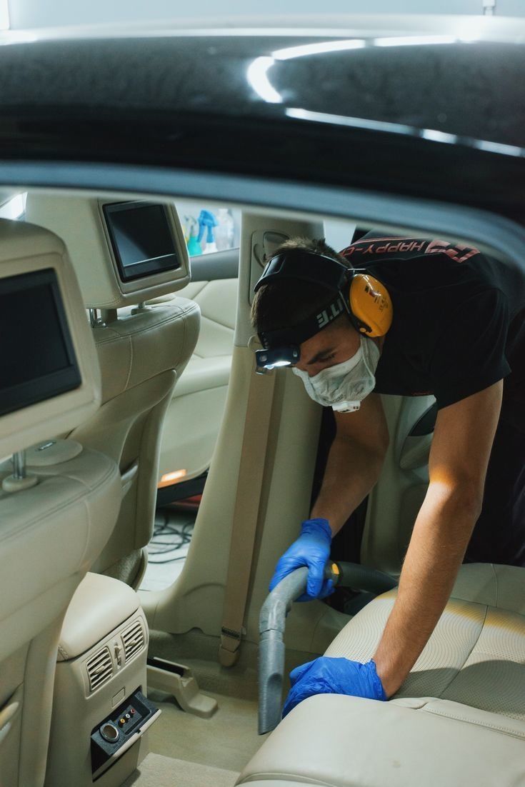 Limpieza profunda de autos: Técnico aspirando asiento trasero