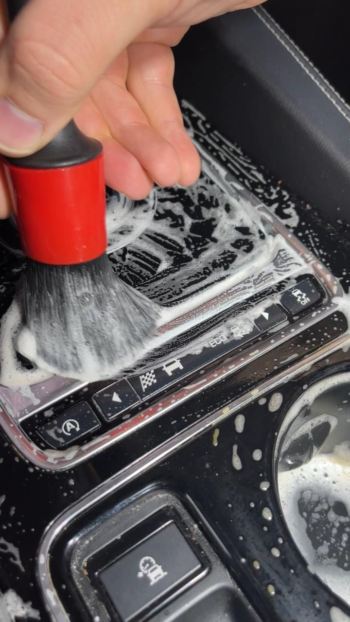Lavado de interiores de autos: Cepillo con espuma sobre consola interior