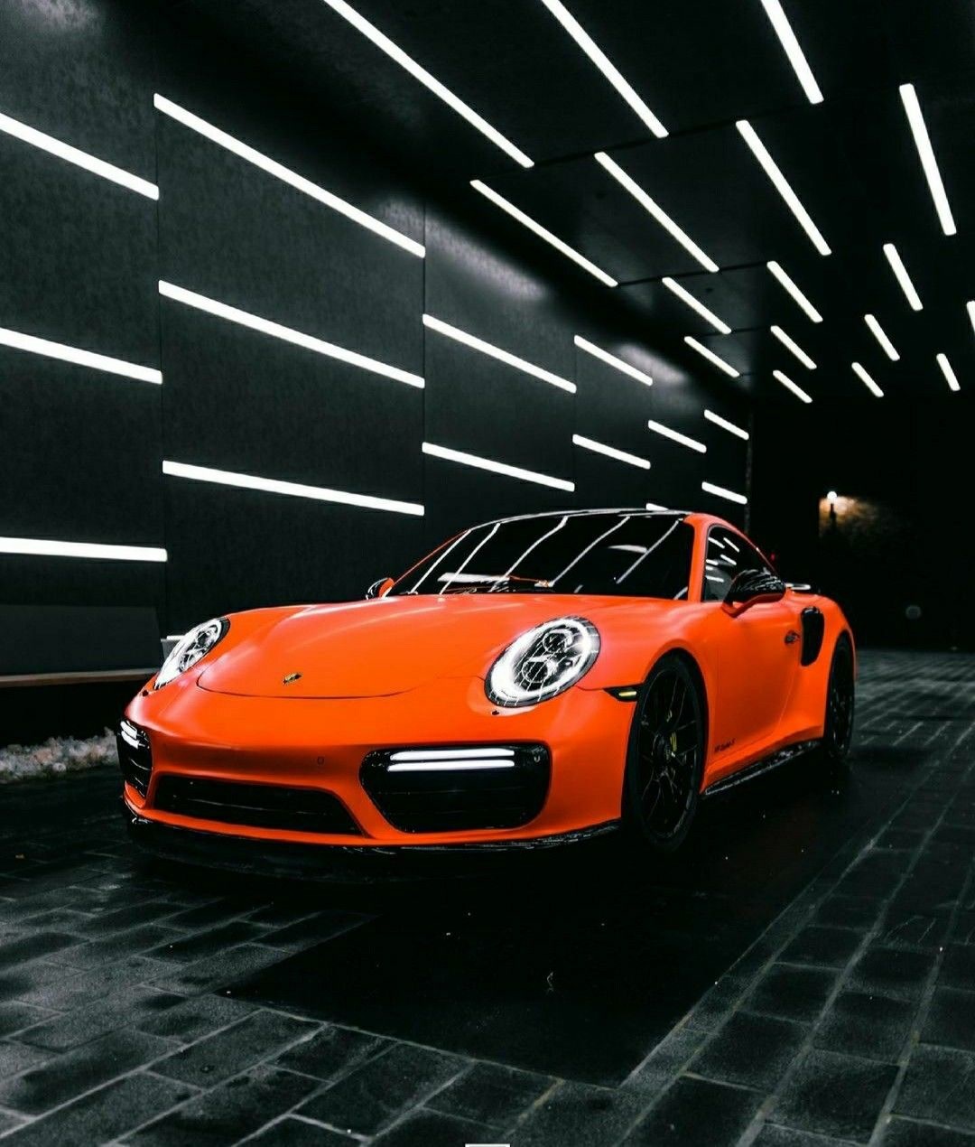 Porsche 911 naranja en estudio de detailing oscuro