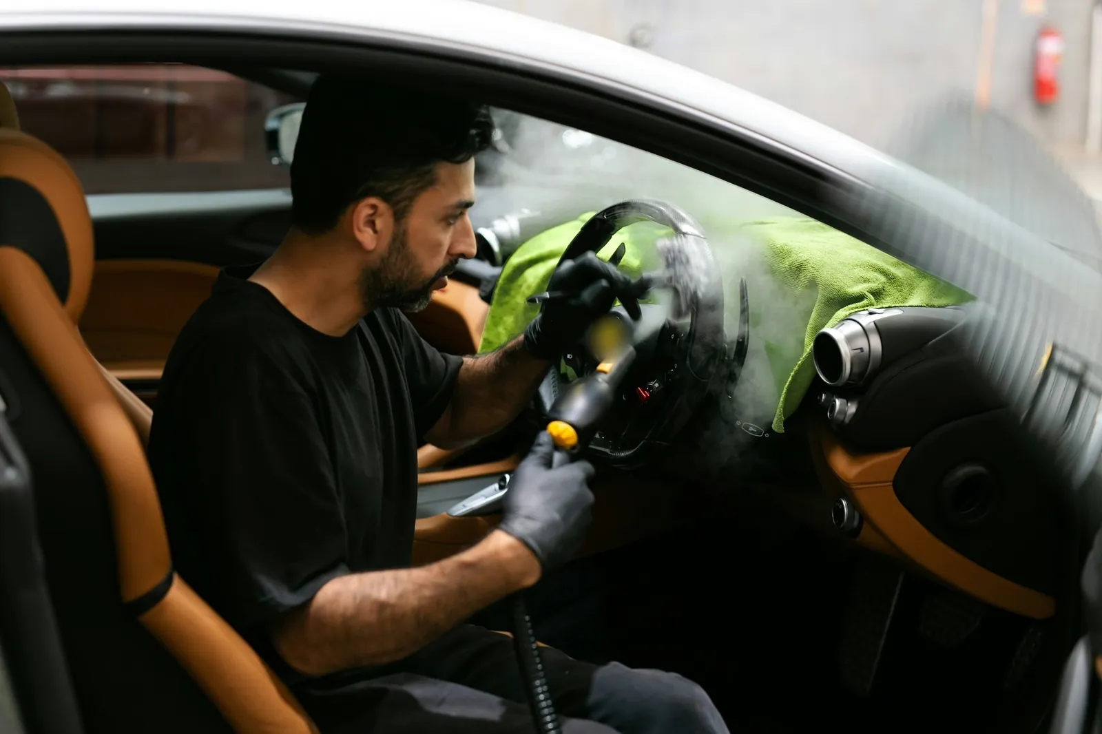 Quita olores auto: detallador sanitizando la cabina con limpiadora de vapor