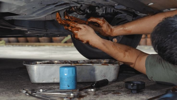 Manos trabajando bajo el chasis (engrase)